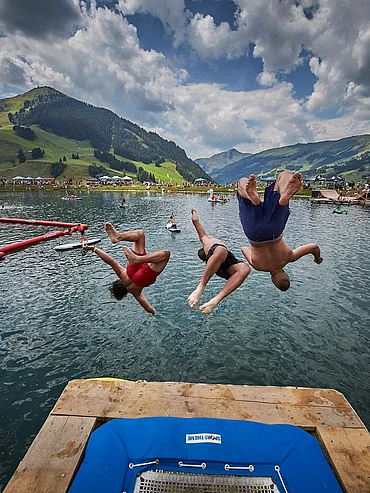 rei Personen springen synchron von Trampolin in See bei Sommerveranstaltung