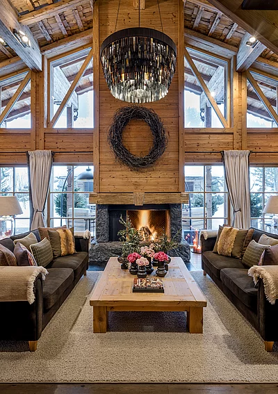 Gemütliches Wohnzimmer mit Kamin, Bluemendekoration und Panoramafenstern im Chalet Die Schmiedalm.