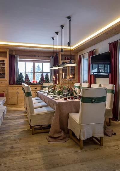 Festlich gedeckter Essbereich im alpinen Chalet Die Schmiedalm mit Kaminofen und Holzmöbeln.
