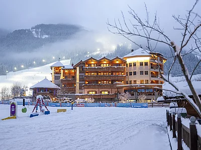 Winterliche Abendstimmung vom Skihotel der Unterschwarzachhof in Saalbach Hinterglemm mit tiefverschneiter Landschaft.