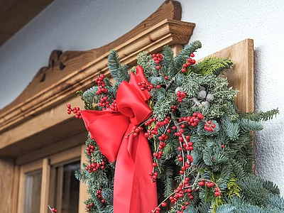 weihnachtliches Gesteck mit roter Schleife am Holzfenster des Hotel Unterschwarzachhof
