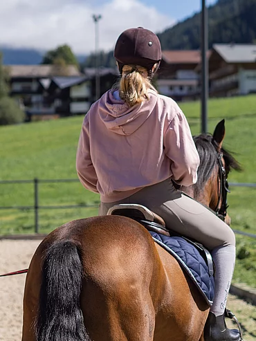 Reiterin auf einem Pferd am Reitplatz des Hotel Unterschwarzachhof
