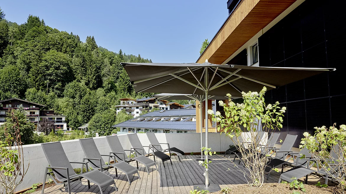 Terrasse mit Liegen und Sonnenschirm Mitarbeiterwohnhaus Unterschwarzachhof Saalbach Hinterglemm