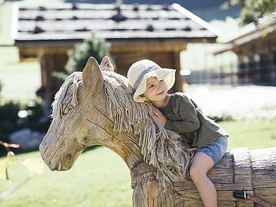 Kleinkind auf Holzpferd am Minibauernhof vom Hotel Unterschwarzachhof