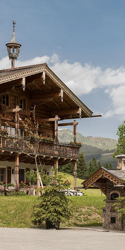 Traditionelles alpines Holzchalet die Schmiedalm mit Balkon und Blick auf grüne Berglandschaft.