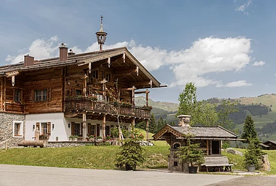 Traditionelles alpines Holzchalet die Schmiedalm mit Balkon und Blick auf grüne Berglandschaft.