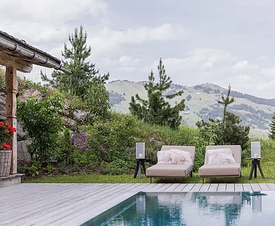 Poolterrasse mit Liegen und Bergblick vor dem Chalet die Schmiedalm in den Alpen.