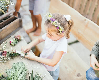 Kinder beim Blumenkranz binden in der Kinderalm im Hotel Unterschwarzachhof