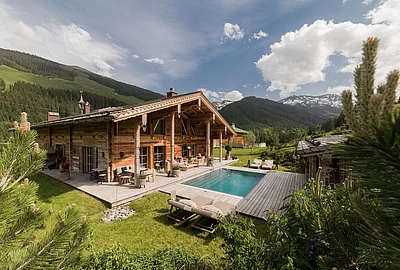 Sommerliches Luxus-Chalet mit Außenpool, Liegestühlen und Alpenpanorama - Die Schmiedalm Saalbach Hinterglemm.