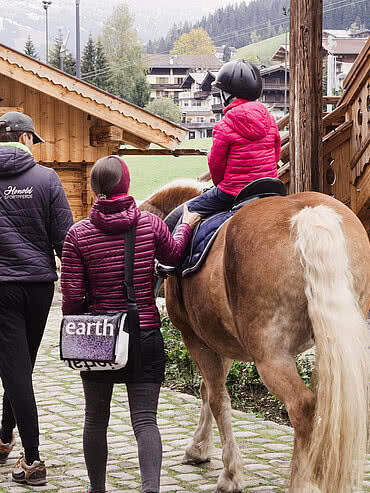 Child being guided on a horse, in the Hotel Unterschwarzachhof