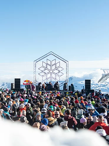 Outdoor-Konzert bei Rave on Snow mit tanzender Menge und Schnee unter Flutlicht