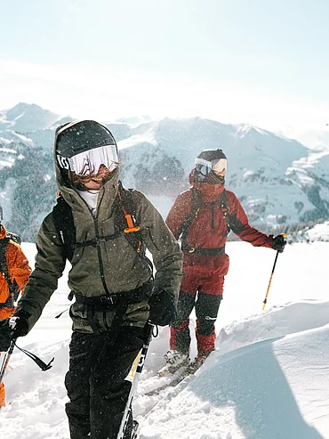 Drei Jugendliche beim Freeride-Aufstieg im Tiefschnee mit Panorama-Bergblick