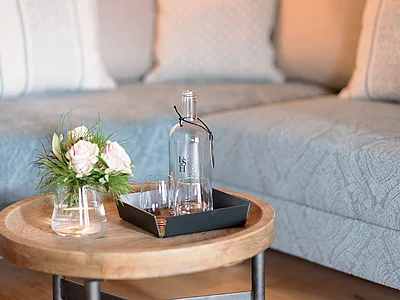 Beistelltisch mit Wasserflasche und Blumen in der Erkersuite im Hotel Unterschwarzachhof